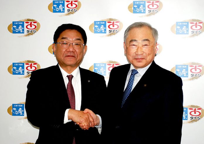 握手を交わすさとの雪食品の植田滋社長㊧と太子食品工業の工藤茂雄社長
