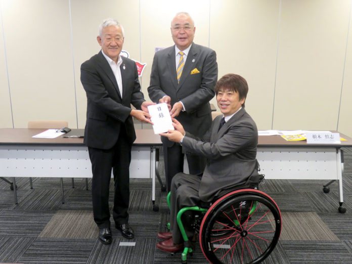 藤尾政弘理事長（'１７大阪実行委員会）から元日本代表の根木慎志氏に目録が手渡された（関西パラアスリート応援プロジェクトへの寄付金贈呈式）