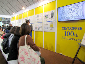 期間限定カフェ「キーコーヒー100周年カフェ」(東京ドーム)の順番待ちスペース。100年の歩みを示すパネル展示やアニメ放映も(第19回 東京国際キルトフェスティバル―布と針と糸の祭典―)