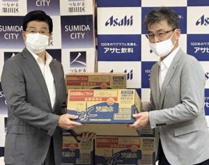 「おいしい水 天然水 長期保存水(災害備蓄用)」のカートンを持つ山本亨墨田区長㊧とアサヒ飲料の南川元司部長