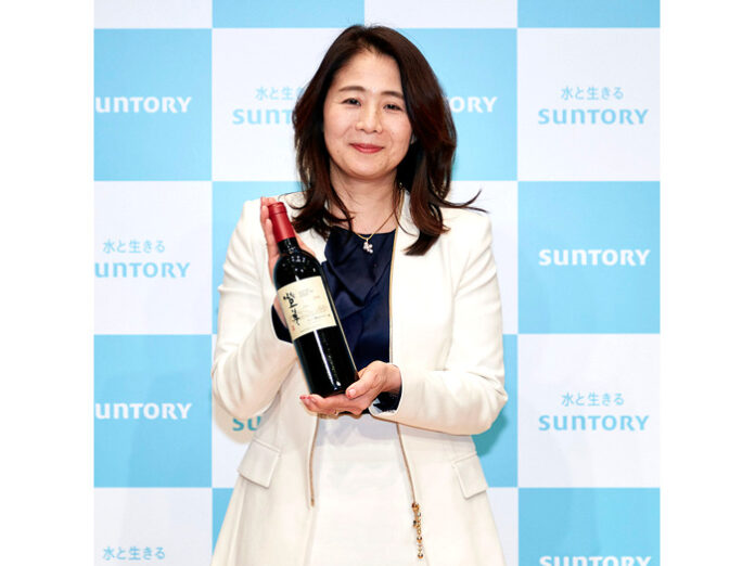 吉雄敬子社長。手にするのは日本ワイン「登美」（サントリーワインインターナショナル）