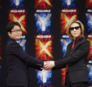 YOSHIKIさんと握手する日本コカ・コーラの島岡芳和マーケティング本部スパークリングフレイバーズカテゴリー事業本部長（左）
