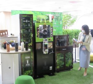 東京建物7階執務室内に設置されるコーヒーマシンと高速ボトル洗浄機。説明する東京建物の阿部里紗子ビルマネジメント第一部主任。