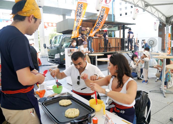 社員に焼き方を教わる外国人観光客