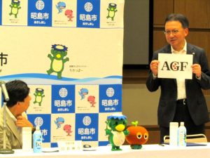 AGFのロゴマークの3つの赤い丸について臼井市長に説明する島本社長 - 食品新聞 WEB版（食品新聞社）