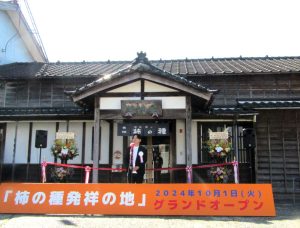 「新潟・長岡 柿の種発祥の地」の前で挨拶する阿部幸明社長 - 食品新聞 WEB版（食品新聞社）