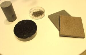 左からCO2吸収済みCO2吸収材を活用したコンクリートブロック道路などに使われるアスファルト舗装をくりぬいたブロックCO2吸収材床タイル 左からCO2吸収済みCO2吸収材を活用したコンクリートブロック、道路などに使われるアスファルト舗装をくりぬいたブロック、CO2吸収材、床タイル
