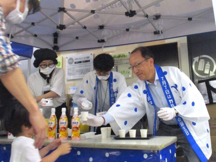 試飲を勧めるアサヒ飲料の米女太一社長（右）