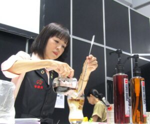 ショットのフレームドオレンジホワイトチョコレートのコーヒーシロップ2種とアーモンドミルクを合わせたドリンクづくりを実演する富田氏 「ショット」の「フレームドオレンジ」「ホワイトチョコレート」のコーヒーシロップ2種とアーモンドミルクを合わせたドリンクづくりを実演する富田氏