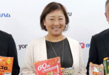 伊藤ハム米久HD 初フレーバーの次は初増量企画 間断なく企画投入で数量増へ 好評の「アルトバイエルン 肉肉味」と米久60周年記念商品を手にする中嶋祐子常務