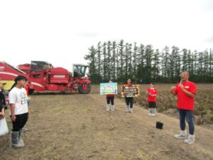 じゃがいも収穫ファンミーティングin北海道で参加者に挨拶するカルビーの野堀和哉コーポレートコミュニケーション本部グループ広報部部長右 「じゃがいも収穫ファンミーティングin北海道」で参加者に挨拶するカルビーの野堀和哉コーポレートコミュニケーション本部グループ広報部部長(右)