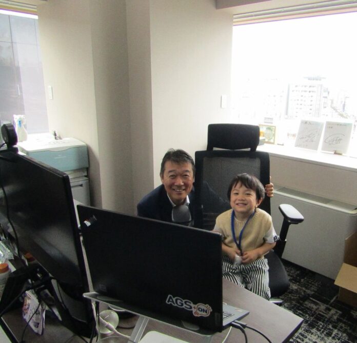 社長室で社員の子どもと写真に収まる川原浩社長
