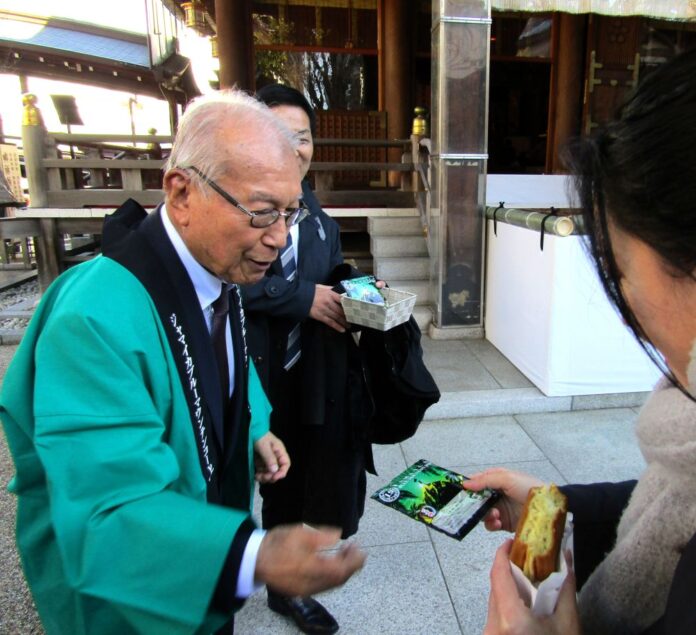 参拝客に「ブルーマウンテンNo.1」のドリップバッグを手渡す上島達司会長