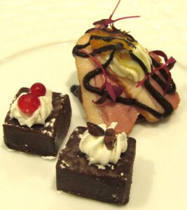 特製カカオプレートに盛られる「パプアニューギニア産カカオ豆を使用した生チョコレート」（左）「インドネシア産カカオ豆を使用した生チョコレート」（右下）「鴨肉とクリームチーズのブリニ」（右上）