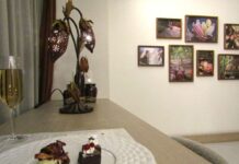 ロッテ、農園などに放置・廃棄されがちなカカオの実を活用 かわいらしい形状に新たな価値創出して産地と消費者をつなぐ 「Cacao Room」のハイカウンターで「カカオポッドランプ」が灯り、特製カカオプレートとスパークリングワインが並ぶ。背景に、実際のカカオ農園で撮影した写真を飾るアートギャラリー