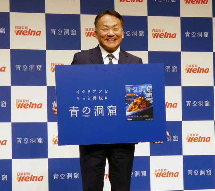 ブランドロゴを掲げる岩橋恭彦社長