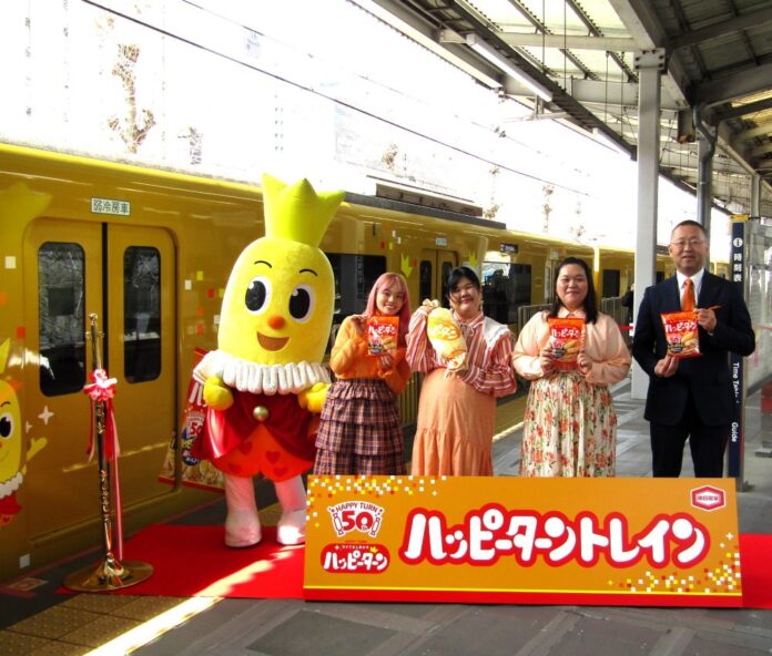 3月23日、京急品川駅（東京都港区）3番線ホームで開催されたオープニングセレモニーに臨んだ亀田製菓の髙木政紀社長COO（右）と、ゲストに招かれたぼる塾