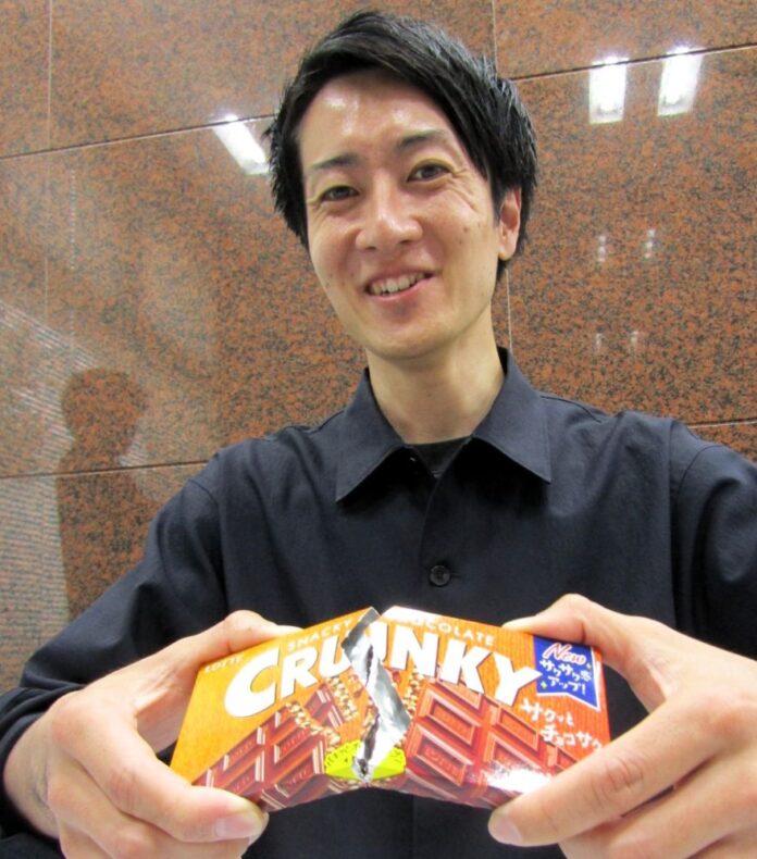板タイプ「クランキー」を箱ごと割るマーケティング本部第一ブランド戦略部チョコレート企画課主査の樋口佑介さん