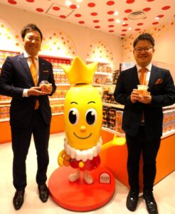 左から尾関太一郎国内米菓マーケティング部部長、「ハッピーターン」の公式キャラクター「ターン王子」のモニュメント、歴舎（れきしゃ）直輝マーケティング戦略部米菓スナック第2グループマネージャー