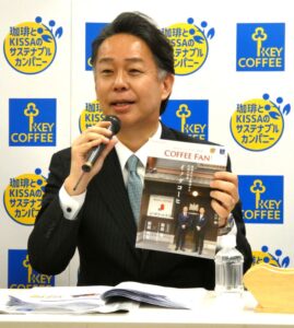 「Rantepao Meeting ～2026年3月期 決算説明と事業活動のご報告～」 に臨んだ柴田裕社長。イノダコーヒを特集した広報誌「COFFEE FAN」を紹介する