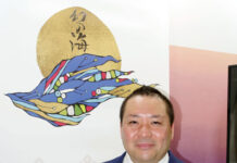 朝倉海苔店 5万分の1枚を厳選 最高級品「幻の海」 「幻の海」を手にする朝倉取締役。背景のアートは小野純一氏が手掛けた