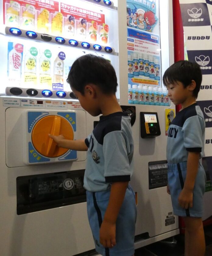 専用ハンドルを回してガチャガチャ体験する幼児