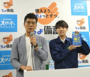 左からサミットの岡田崇取締役常務執行役員と「備災ガイドBOOK」を紹介するサミットストア朝霞台店の仁木涼生氏
