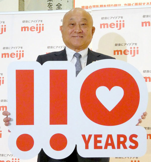 110周年ロゴを掲げる松田克也社長CEO