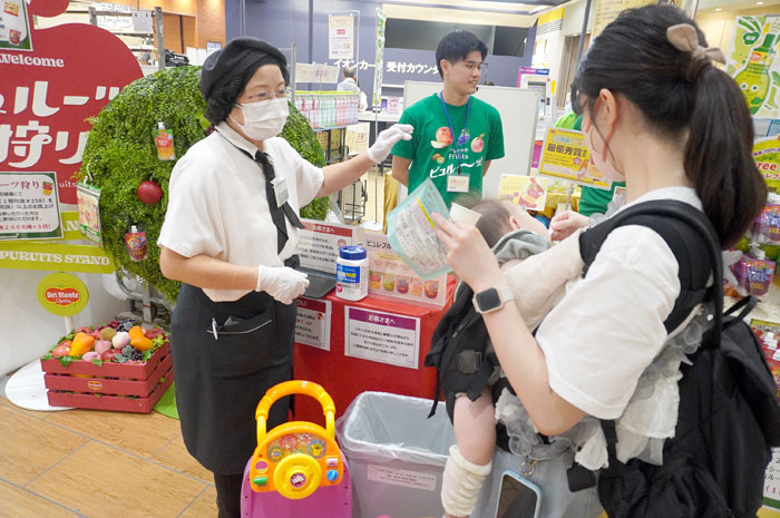 赤ちゃんをだっこしながら「ピュレフルーツ」を試食(キッコーマン食品ブース)